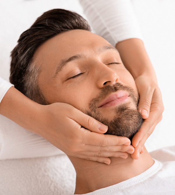 man receiving a facial massage with relaxed expression promoting wellness and rejuvenation in skin care routine